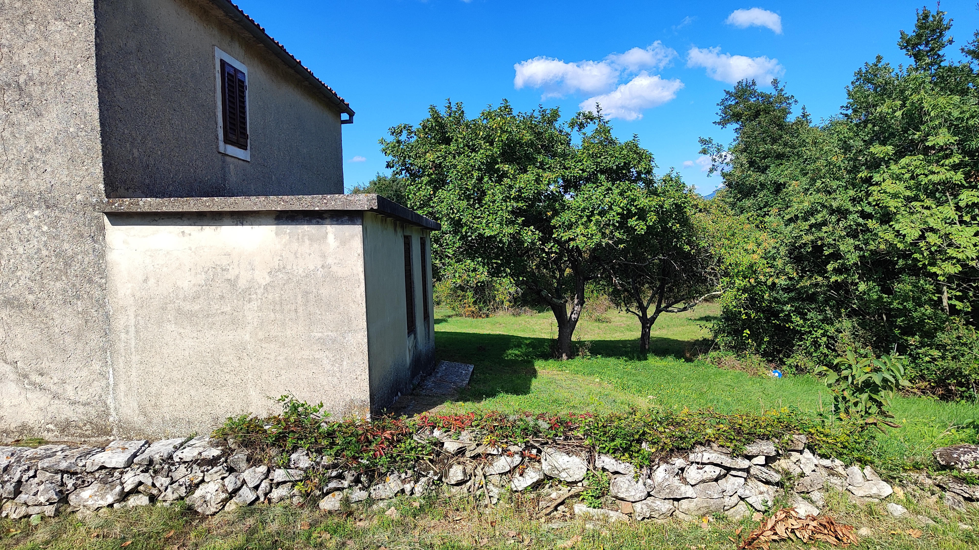 Existing building with stone wall and trees